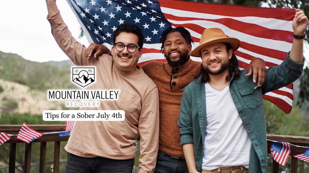 Three smiling friends stand on a deck holding an American flag. Text reads "Mountain Valley Recovery: Tips for a Sober July 4th." Festive, supportive tone.