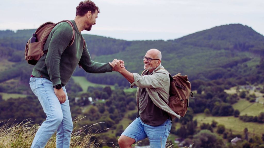 Father and Son Helping Each Other On Family Hike in Recovery from Addiction