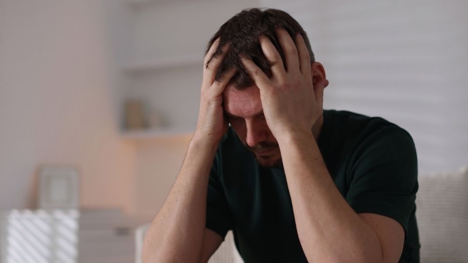 Signs and Symptoms of Depression in Men hero image of a man holding his head in his hands.
